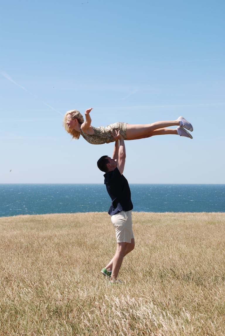 A couple enjoying a playful moment by the ocean in summer, embodying freedom and happiness.