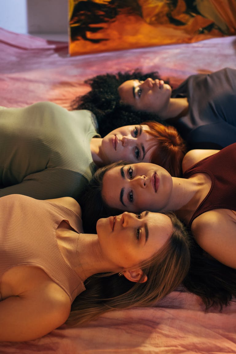 A creative and empowering portrait of four women lying together in a studio.