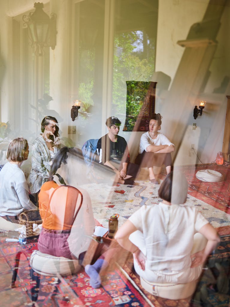 A diverse group sits in a circle during a relaxed meditation session indoors.
