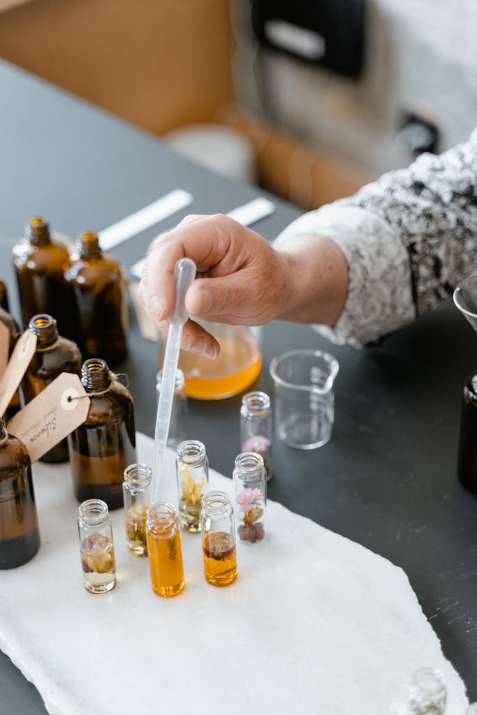 A person blending various natural essential oils in small bottles for aromatherapy.