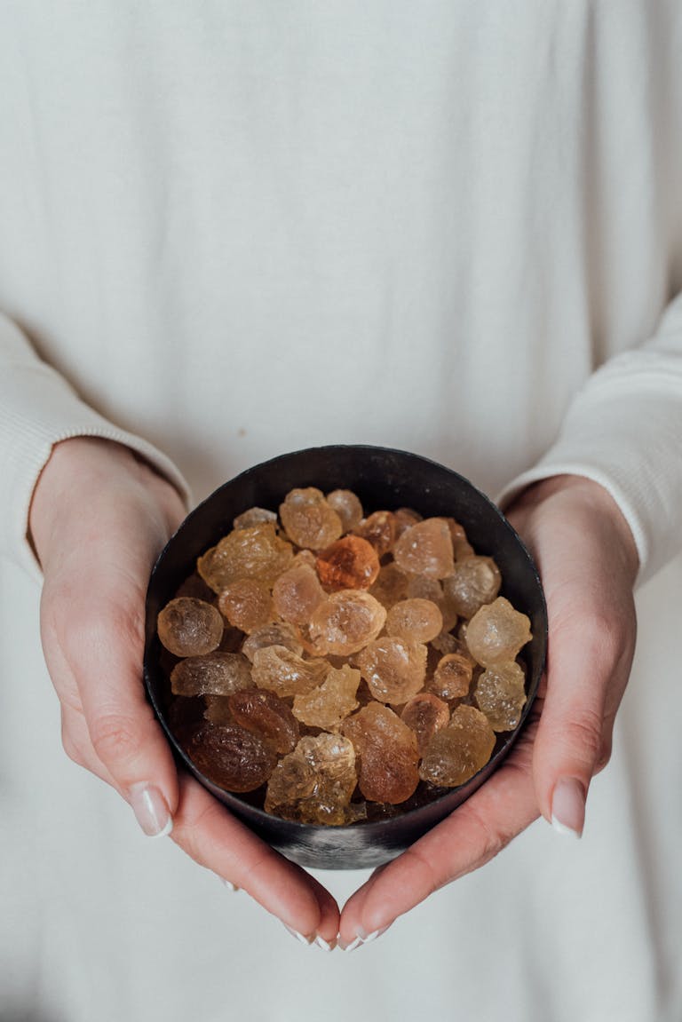Hands gently holding a bowl filled with healing crystals for holistic therapy.