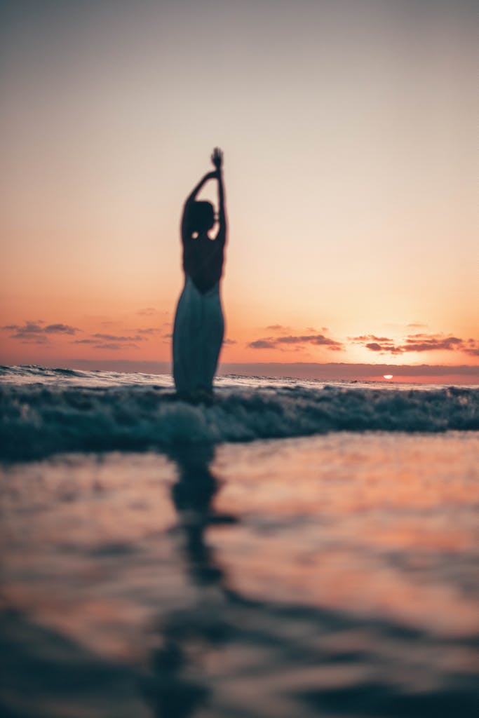 Serene silhouette of a person at Malibu beach during sunset with soft ocean waves.