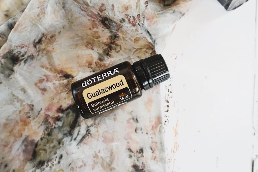 Guaiacwood essential oil bottle on a delicate textured background, styled in a flat lay.